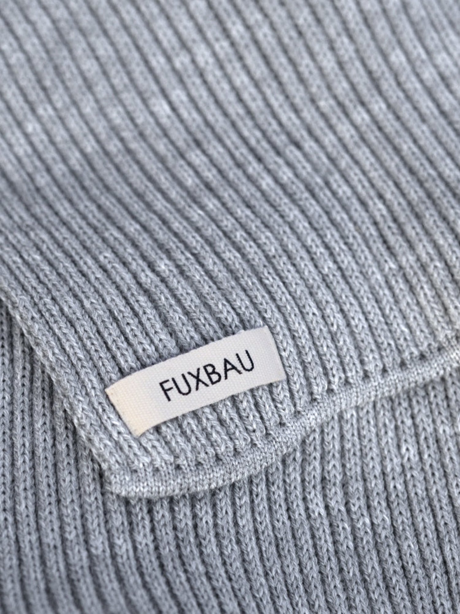 Detailansicht eines FUXBAU Merino Schal in Grau mit Brandlabel aus Biobaumwolle
