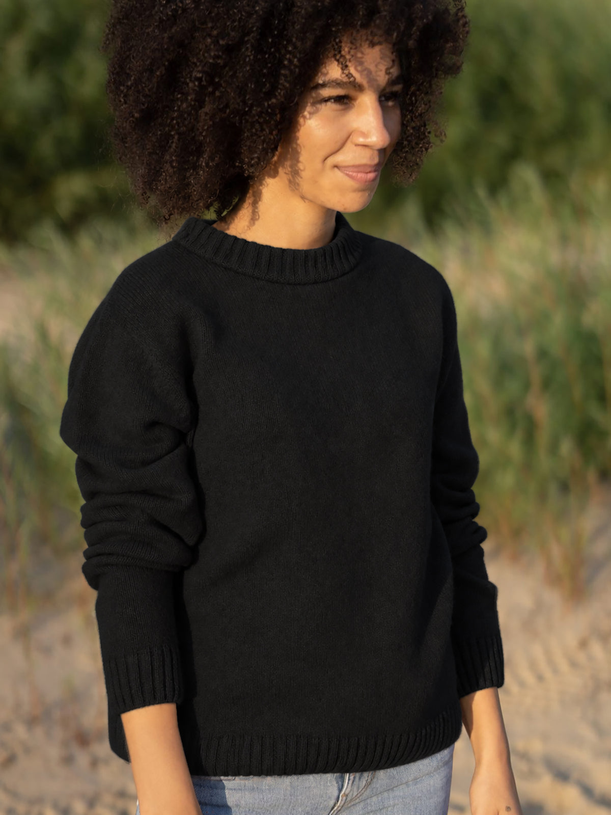 Jacky trägt den nachhaltigen Strickpullover in schwarz aus 100% Merinowolle und made in Germany.