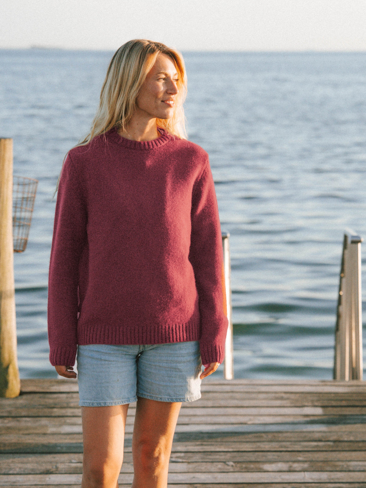 Frauen Merino Strickpullover in Bordeaux aus mulesingfreier Merinowolle getragen am Meer