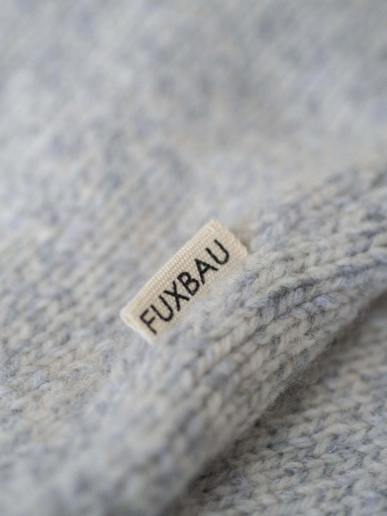 FUXBAU Label auf der graumelierten Strickweste aus Merinowolle – nachhaltige, faire Produktion Made in Germany