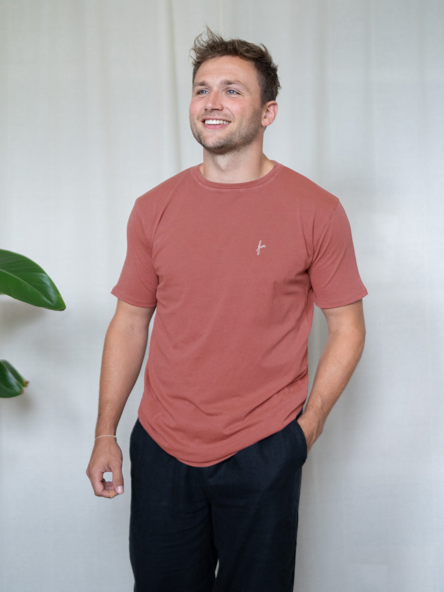 Junger Mann trägt das nachhaltige T-Shirt in rot aus Biobaumwolle von FUXBAU