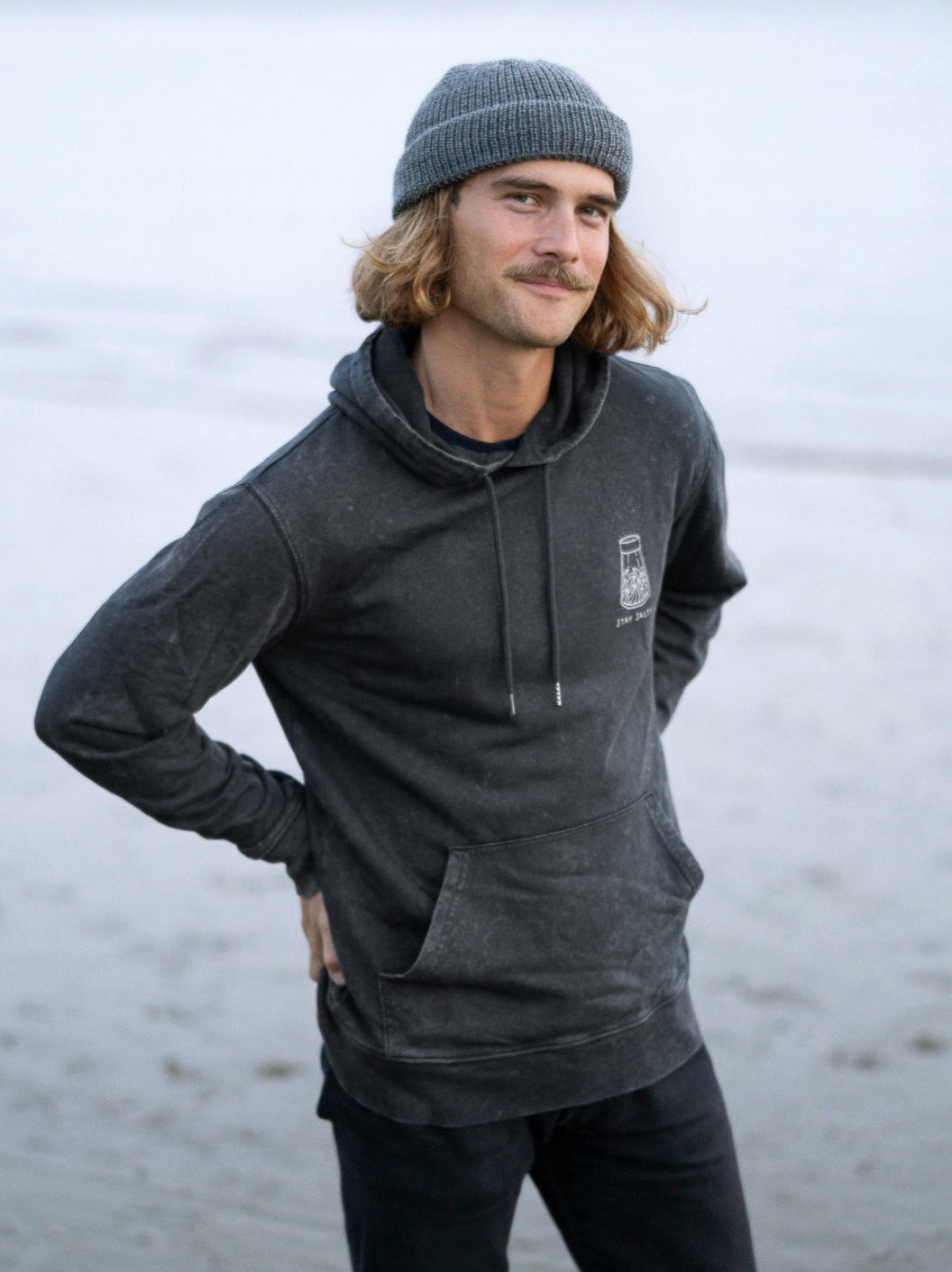Unser Freund Kelsey trägt unseren nachhaltigen FUXBAU Stay Salty Hoodie in salzblau designed by Pia Himmelein aus 100% GOTS zertifizierter Biobaumwolle