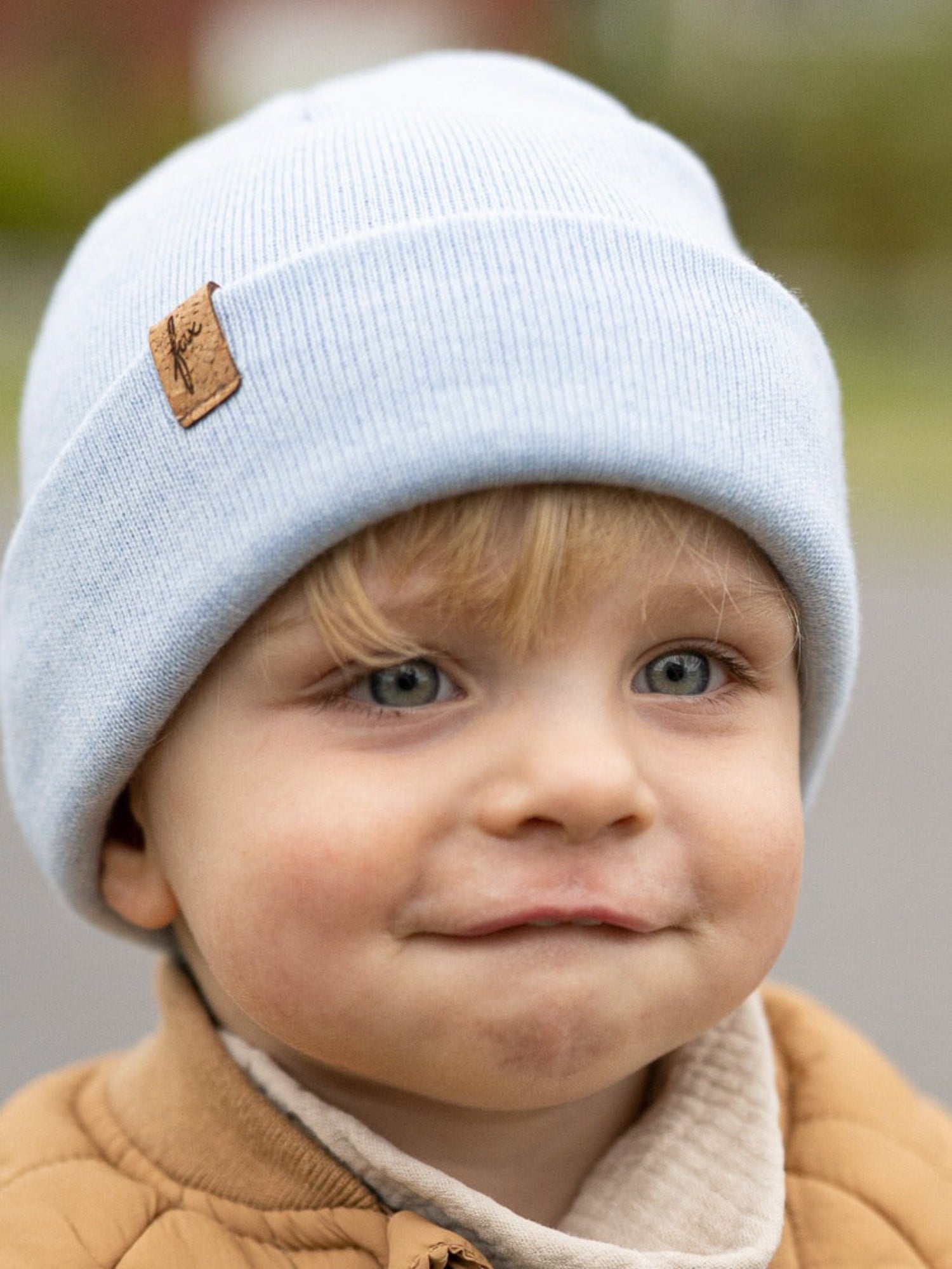 Kind mit eisblauer FUXBAU Kinder Merino Kork Beanie – nachhaltige Mütze aus 100% Merinowolle, fair produziert in Deutschland mit Kork-Patch.