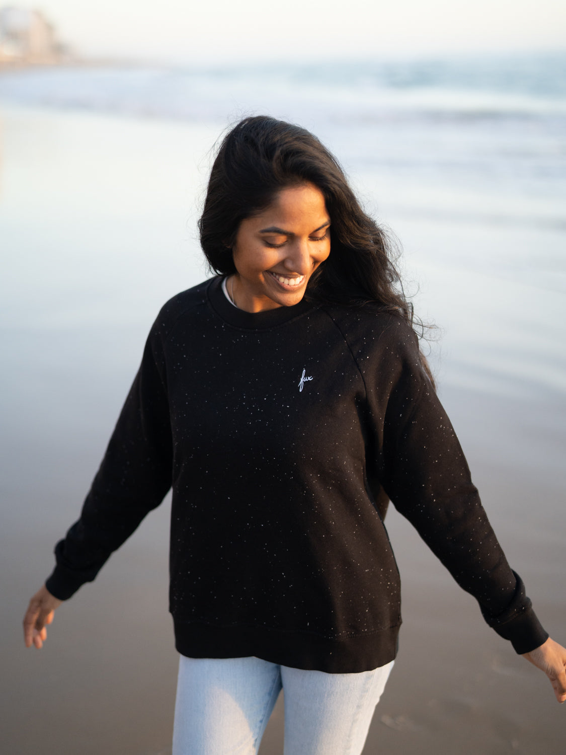 Neelia trägt am Strand unseren FUX Pullover mit neps in schwarz aus Biobaumwolle