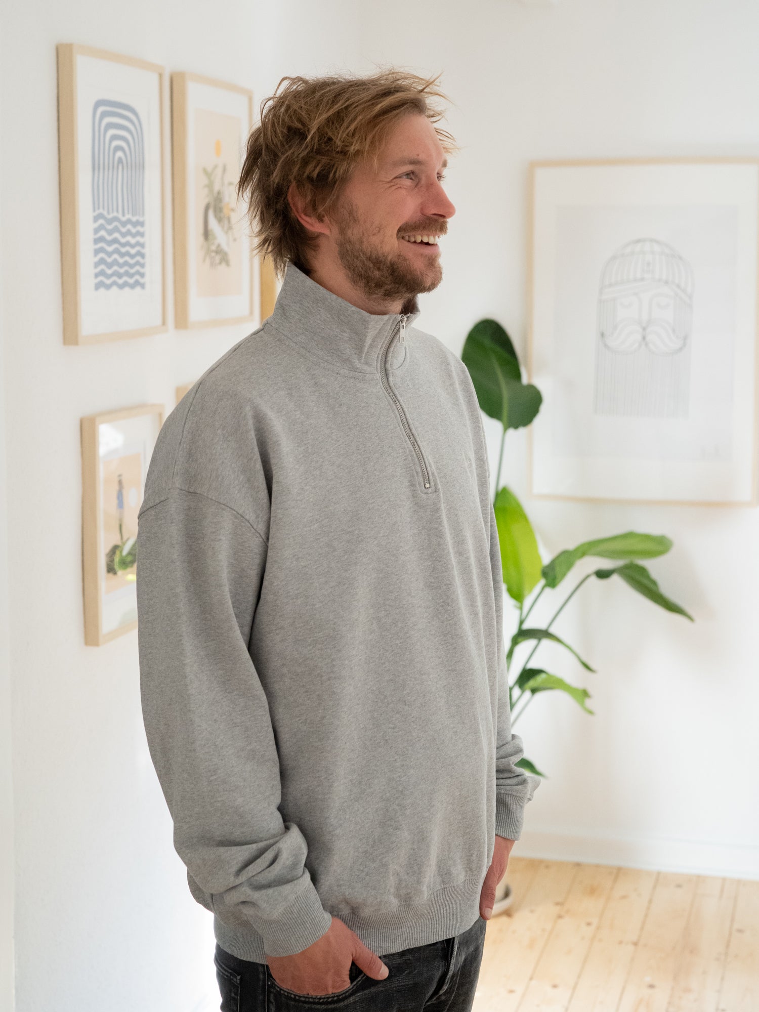 Kenny trägt unseren Fair Fashion Half Zip Sweater in grau aus Biobaumwolle