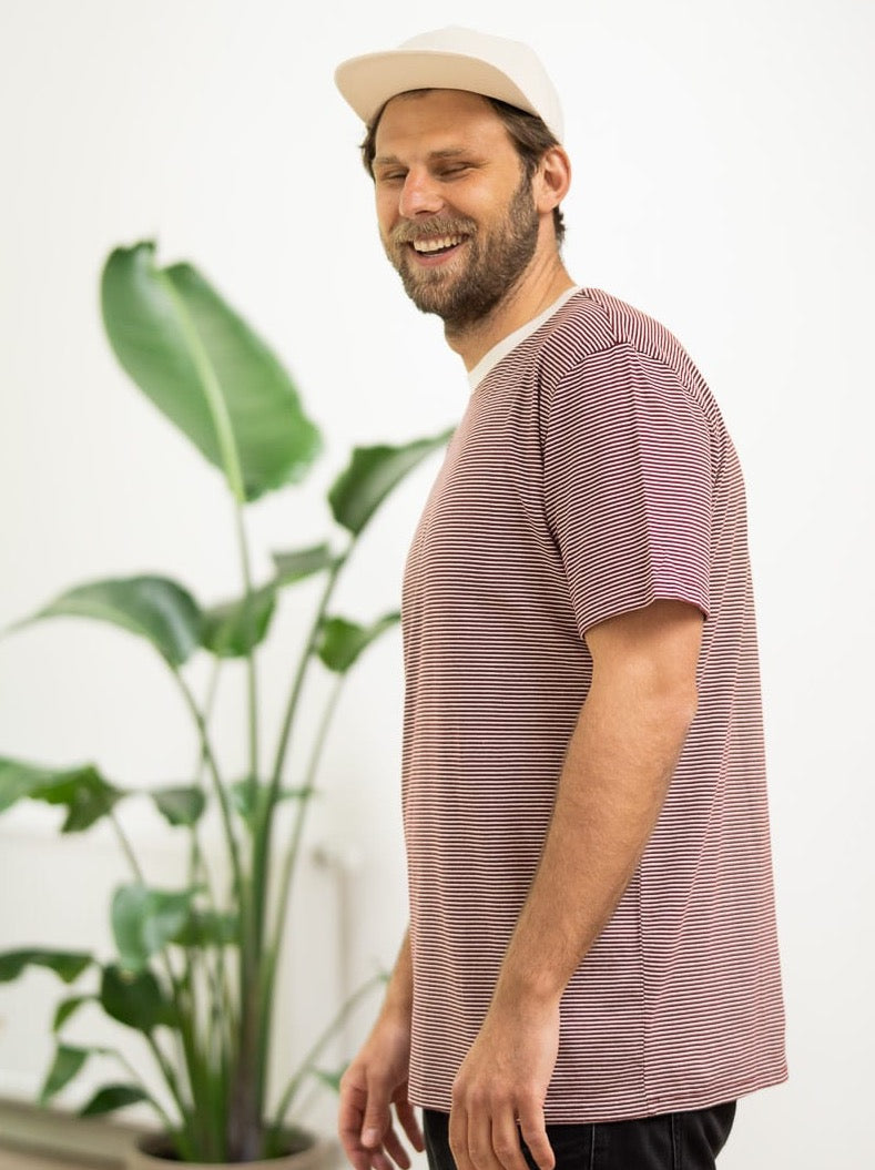 Philipp trägt unser nachhaltiges gestreiftes T-Shirt in bordeaux aus 100% Biobaumwolle made in Portugal