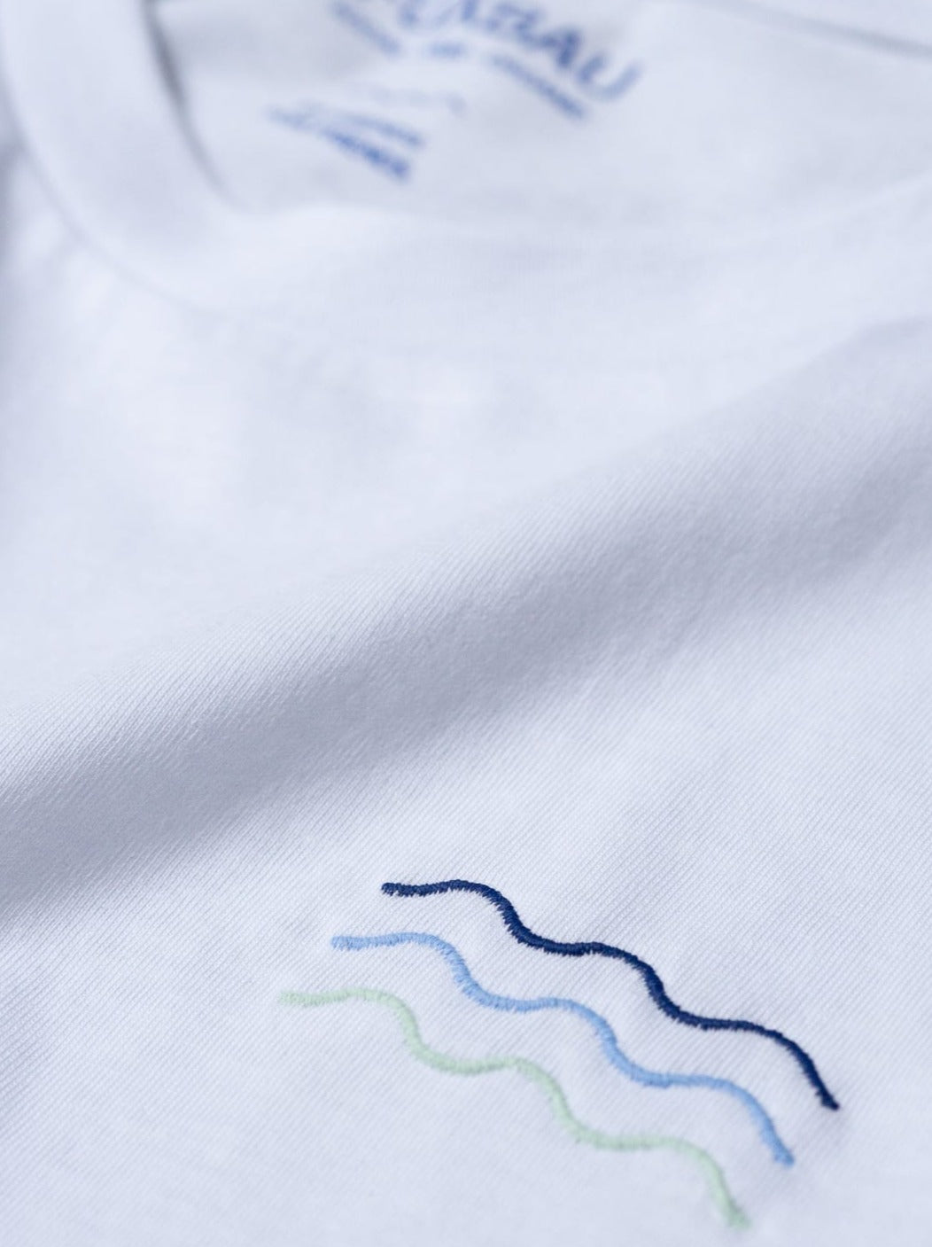 Nachhaltiges Fair Fashion Surf T-Shirt von FUXBAU in weiss mit gestickten Wellen aus 100% Biobaumwolle.