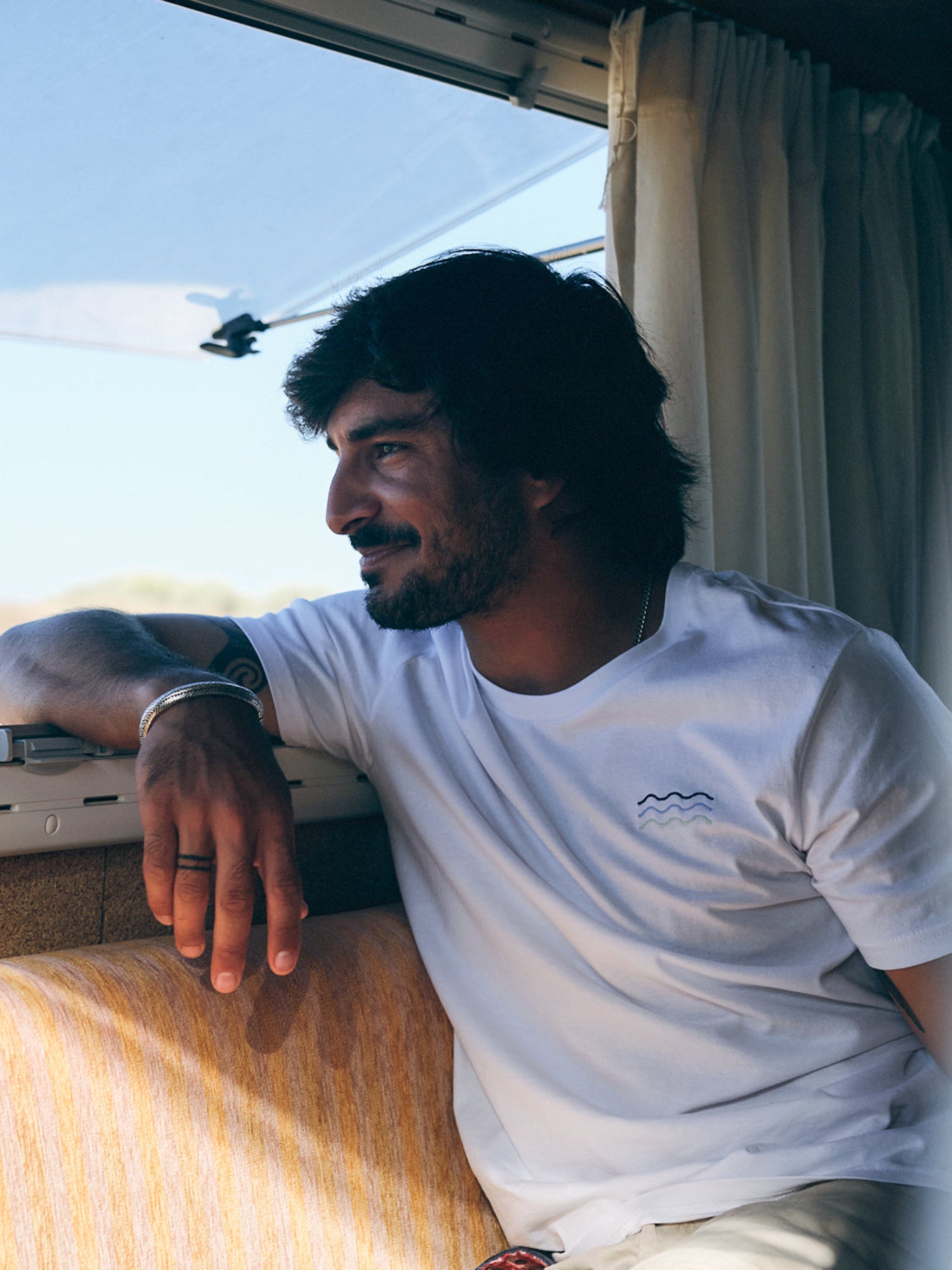 Nachhaltiges Fair Fashion Surf T-Shirt von FUXBAU in weiss mit gestickten Wellen aus 100% Biobaumwolle getragen von Alejandro.